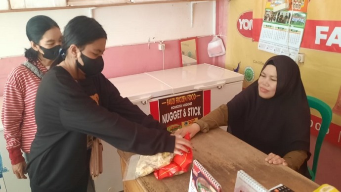 Siti Fatimah (kanan) melayani pembeli frozen food di toko miliknya, Jalan Tjilik Riwut kilometer 1,5 Kelurahan Palangka, Kecamatan Jekan Raya. (FOTO : HAFIDZ/PROKALTENG.CO)