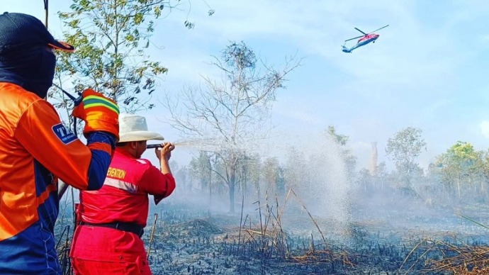 Para petugas BPBD saat melakukan pemadaman lahan yang terbakar, juga terlihat Helikopter water bombing juga terlihat melakukan pengeboman air, ini terlihat Senin (21/8). (FOTO : BPBD UNTUK KP)